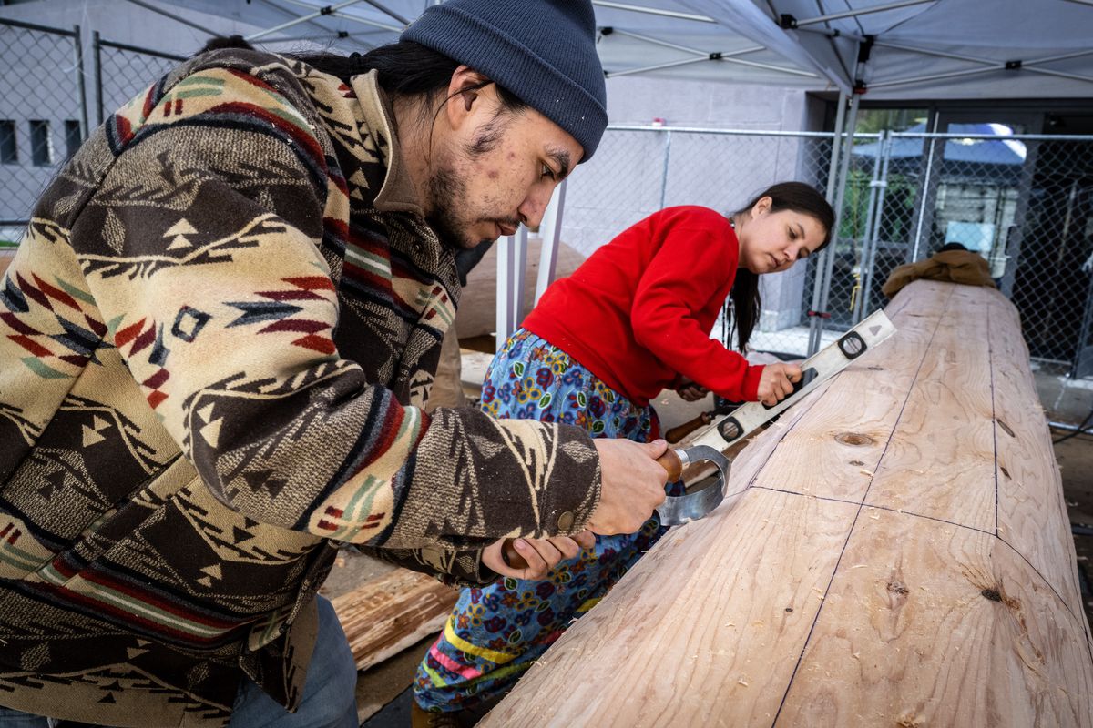 Louis Bates, a Spokane Tribe member, and Crystal Conant, an Arrow Lakes and Sanpoil Tribe member, use hand tools to carve one of two dugout canoes being crafted by members of the Upper Columbia United Tribes at the Museum of Arts and Culture on Friday.  (COLIN MULVANY/THE SPOKESMAN-REVI)