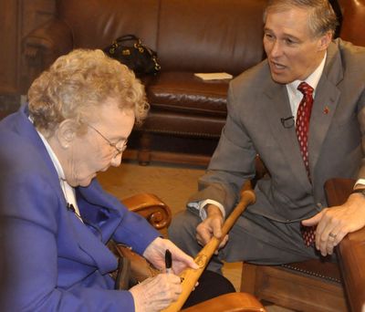 Dorothy Roth, who played in the National Girls Baseball League in 1945, autographs a bat for Gov. Jay Inslee on Tuesday. (Jim Camden)