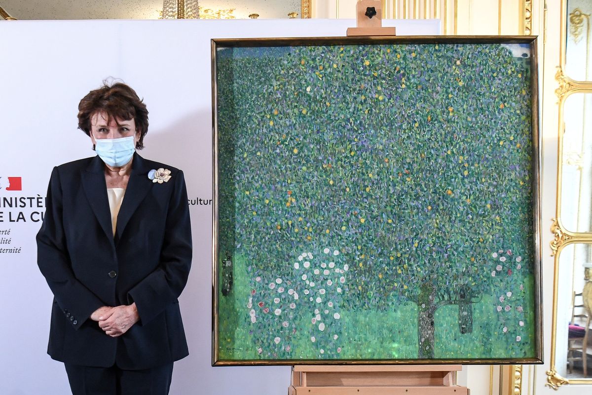 French Culture Roselyne Bachelot poses next to a spoiled oil painting by Gustav Klimt painted between in 1905 called"Rosebushes under the Trees," during a ceremony at the Orsay museum in Paris, Monday, March 15, 2021. The French government hands over a Klimt painting to the grandchildren of the holocaust victim Nora Stiasny stolen by the Nazis during World War II.  (Alain Jocard)