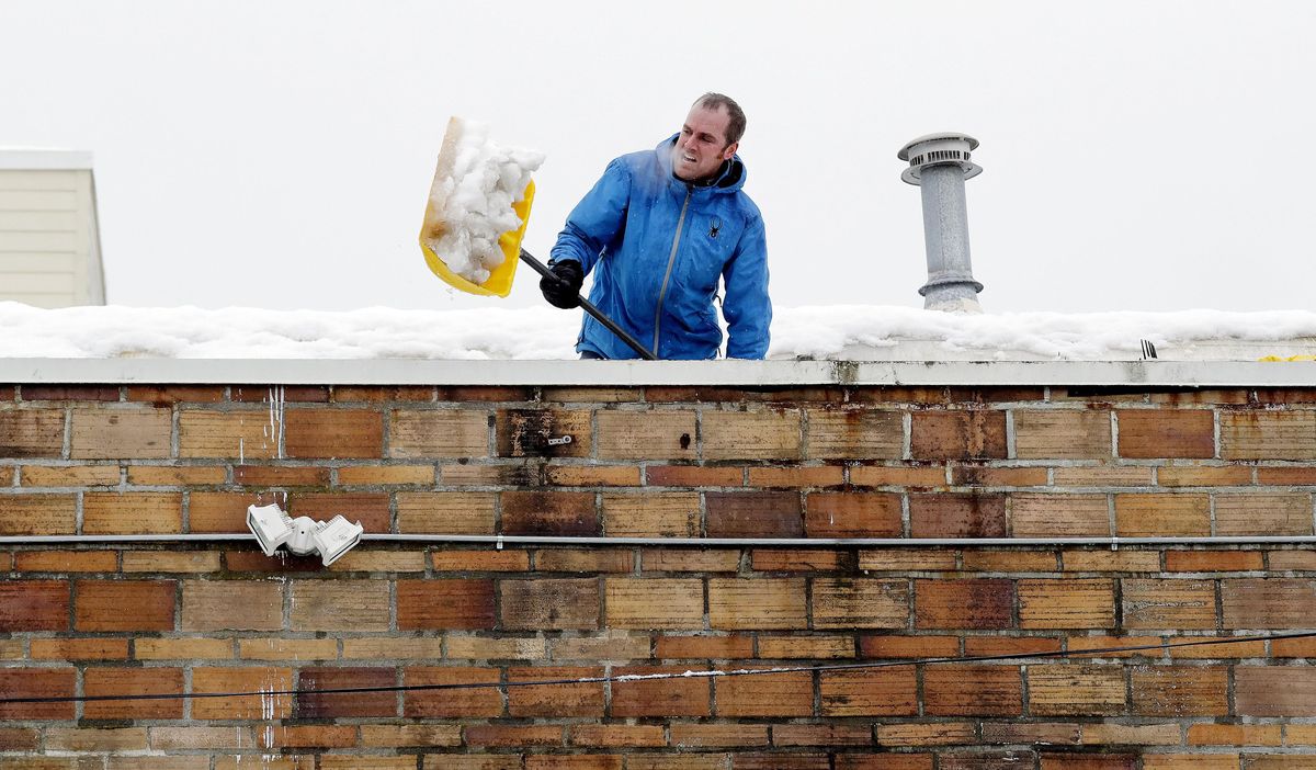 Kyle Piehowski shovels heavy, wet snow off of the roof of a business that was beginning to flood inside after water was caught under melting snow on the flat roof Tuesday, Feb. 12, 2019, in Seattle. The National Weather Service reports that Seattle-Tacoma International Airport has received 20.2 inches of snow so far in February, the snowiest month in more than 50 years. (Elaine Thompson / Associated Press)