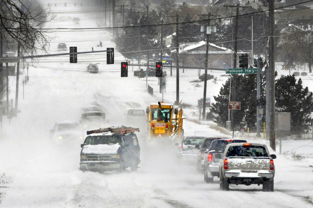 Like chicks tucked behind a mother hen, a line of cars follow a road grader west on 57th Avenue as it clears the heavy snowfall Thursday. The powdery snow was blowing into drifts that made driving and plowing difficult. (Christopher Anderson)