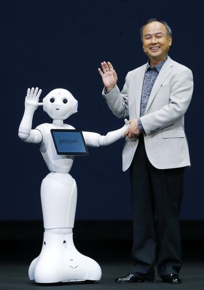 Softbank Corp. President Masayoshi Son and a newly developed robot wave together during an event in Urayasu, Japan, on Thursday. (Associated Press)