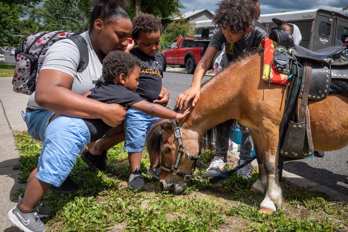 Mom Jalize Jackson and sons Jameel Fletcher, 2, and Zy’Rai Fletcher, 1, inch their way closer to petting a pony during the Martin Luther King Jr. Community Center’s Juneteenth Celebration in 2023 in Spokane.  (COLIN MULVANY/THE SPOKESMAN-REVIEW)