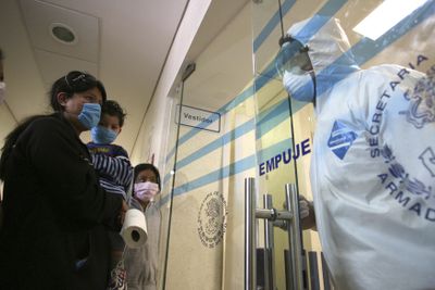 A woman with children speaks to a Navy sailor guarding the entrance to the area where patients with swine flu symptoms are treated in Mexico City Tuesday. The name has spawned worldwide confusion over how the flu strain spreads. (Associated Press / The Spokesman-Review)