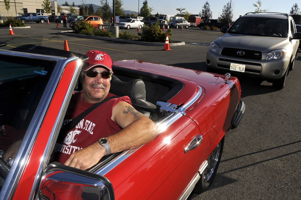 Dave Bambino, of Spokane Valley, has his car top down and his shirt sleeve up as he waits  in line for a flu shot Saturday. 