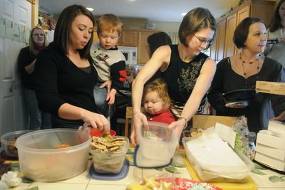 Shelbie Clement and her son James, left, Michelle Aikman, top center, Patty Ragan, right and her daughter Amelia, lower center, gather at Jen Macakanja’s, far left, background, home in north Spokane for a MOMS Club cookie exchange Dec. 17.  (Dan Pelle / The Spokesman-Review)