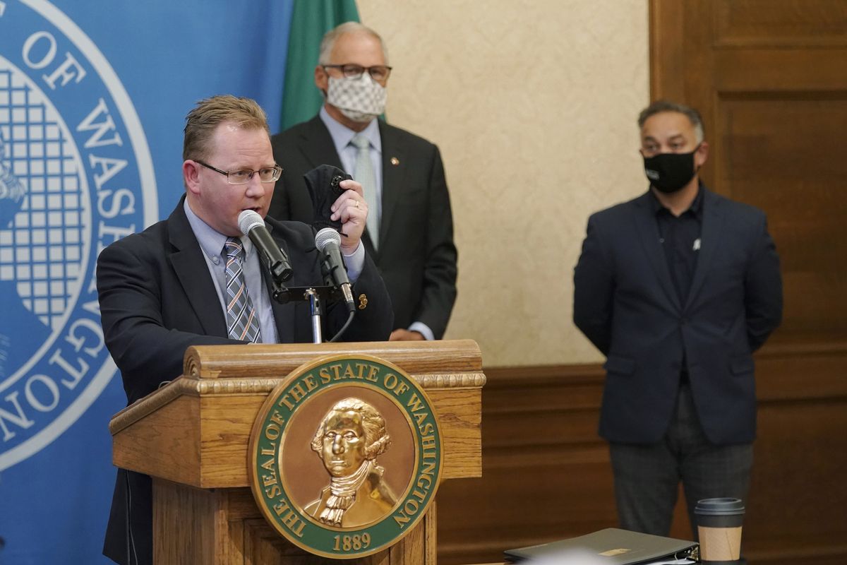 Washington State Superintendent of Public Instruction Chris Reykdal, left, holds up a face mask as he speaks at a news conference, along with Gov. Jay Inslee, center, and Secretary of Health Umair A. Shah, right, at the Capitol, Wednesday, Aug. 18, 2021, in Olympia. Inslee announced that Washington state is expanding its vaccine mandate to include all public, charter and private school teachers and staff, as well as those working at the state’s colleges and universities.  (Ted S. Warren/Associated Press)