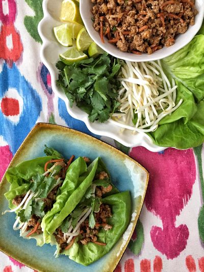 Lettuce cups are filled with an Asian-inspired medley of ground chicken, onions, carrots and water chestnuts, then topped with fresh bean sprouts, cilantro and a squeeze of lime. (Audrey Alfaro)