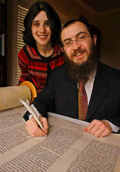 
Rabbi Mendel Lifshitz looks up from an old Torah he is repairing as his wife Esther stands behind him in their home in Boise. 
 (Associated Press / The Spokesman-Review)