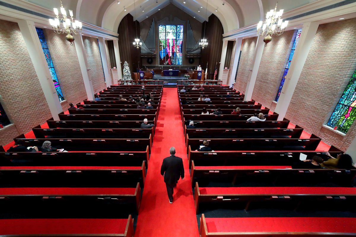Rev. Meredith Mills delivers a sermon from the pulpit for some 30 attendants during the second service of the day in the sanctuary at Westminster United Methodist Church Sunday, Dec. 12, 2021, in Houston. Attendance for the two Sunday services is only about half of the average pre-pandemic turnout of about 160 or 170, Mills says. “It
