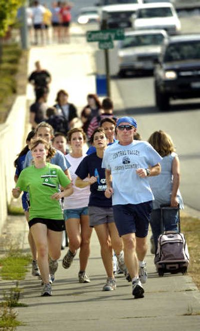 
CV coach Dennis McGuire, right, leads one group of his girls cross country team down Sullivan Road during practice last Thursday. 
 (Holly Pickett / The Spokesman-Review)