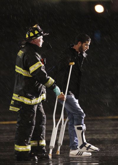 A wounded Libyan fighter is escorted across the tarmac at Logan International Airport in Boston on Saturday. (Associated Press)