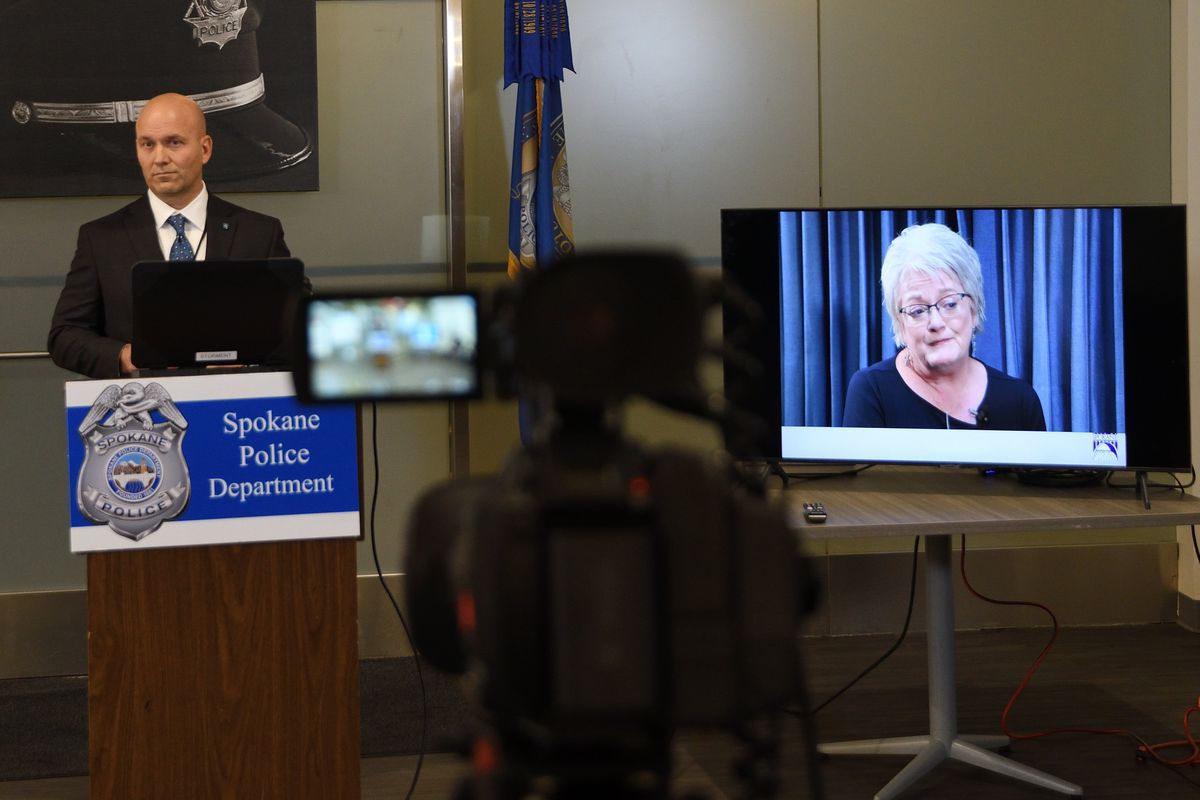 Spokane police Sgt. Zac Storment stands at the lectern Friday during a news conference about the Candy Rogers cold case while John Reigh Hoff’s daughter, Cathie, talks on the TV screen to his left.  (COLIN TIERNAN/THE SPOKESMAN-REVIEW)