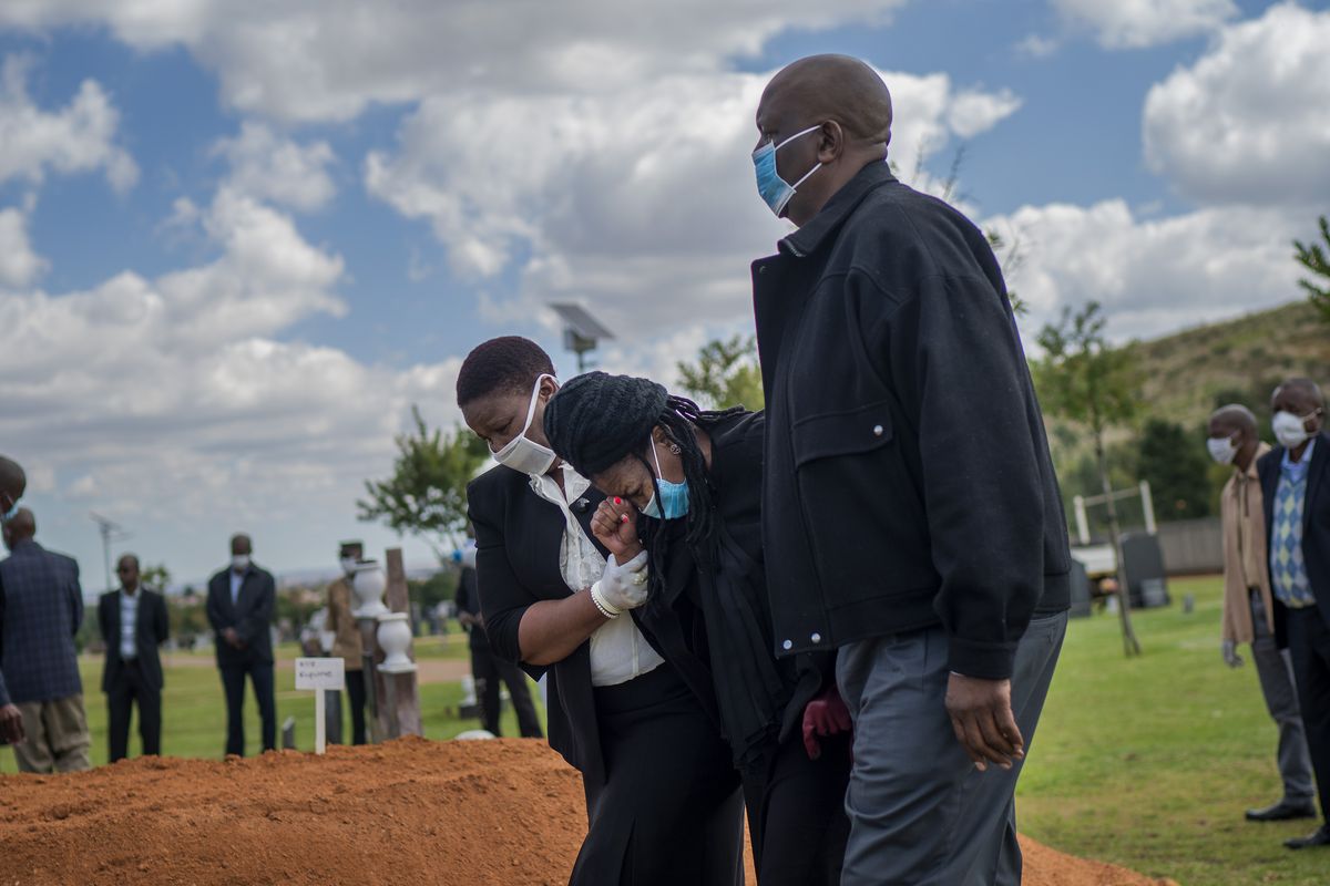 In this Thursday, April 16, 2020 photo, relatives grieve coffee shop manager Benedict Somi Vilakasi, who died of a COVID-19 infection in a Johannesburg hospital, at his burial ceremony at the Nasrec Memorial Park outside Johannesburg. More than two dozen international aid organizations have told the U.S. government they are "increasingly alarmed" that "little to no U.S. humanitarian assistance has reached those on the front lines" of the coronavirus pandemic as the number of new cases picks up speed in some of the world