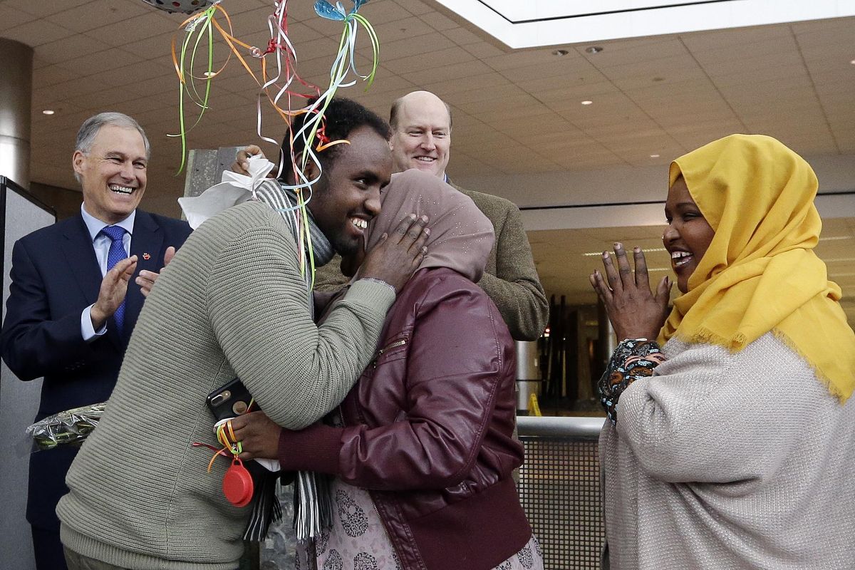 Isahaq Ahmed Rabi, second left, greets extended family members as Washington Gov. Jay Inslee, left, and Port of Seattle Commissioner President Tom Albro applaud shortly after Rabi’s arrival Monday, Feb. 6, 2017, at Seattle Tacoma International Airport in SeaTac, Wash. (Elaine Thompson / Associated Press)