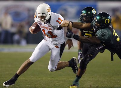 Oklahoma State QB Zac Robinson, left, breaks away from Oregon defenders.  (Associated Press / The Spokesman-Review)