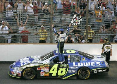 NASCAR driver Jimmie Johnson waves the checkered flag after winning the Nextel Cup Allstate 400 at the Brickyard.
(Associated Press / The Spokesman-Review)