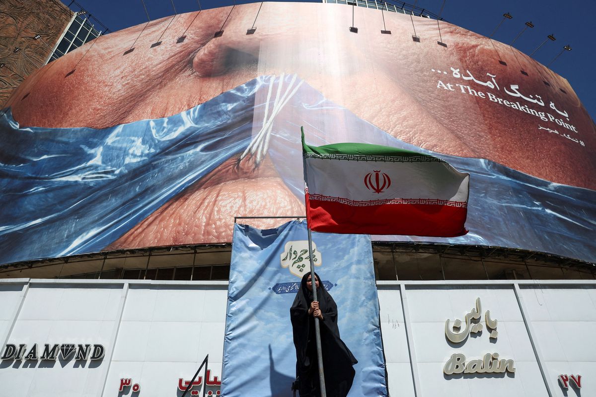 A woman holds an Iranian flag near an anti-U.S. billboard depicting U.S. President Donald Trump and the Strait of Hormuz, in Tehran, Iran, May 25, 2026 (Reuters)