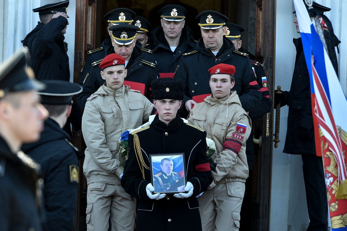 A serviceman carries the photo of Capt. Andrei Paliy, a deputy commander of Russia’s Black Sea Fleet killed in fighting with Ukrainian forces in Mariupol, during a farewell ceremony in Sevastopol, Crimea, on Wednesday.  (UGC)