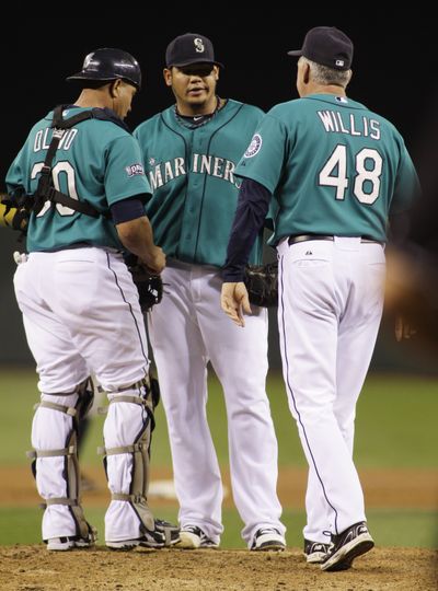 It was a rough night for Felix Hernandez, who is visited by Miguel Olivo, left, and pitching coach Carl Willis. (Associated Press)