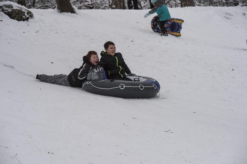 Eathen Currie holds on to his brother, Izeck, as they slide down one of the hills at Manito Park, Sunday, Dec. 25, 2016. (Liz Kishimoto / The Spokesman-Review)