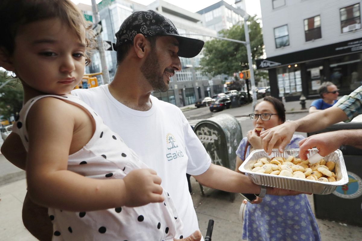 In this July 11, 2019, photo, Syrian refugee and restaurant owner Diaa Alhanoun holds his young daughter, Masa, then 21 months, while offering his wife