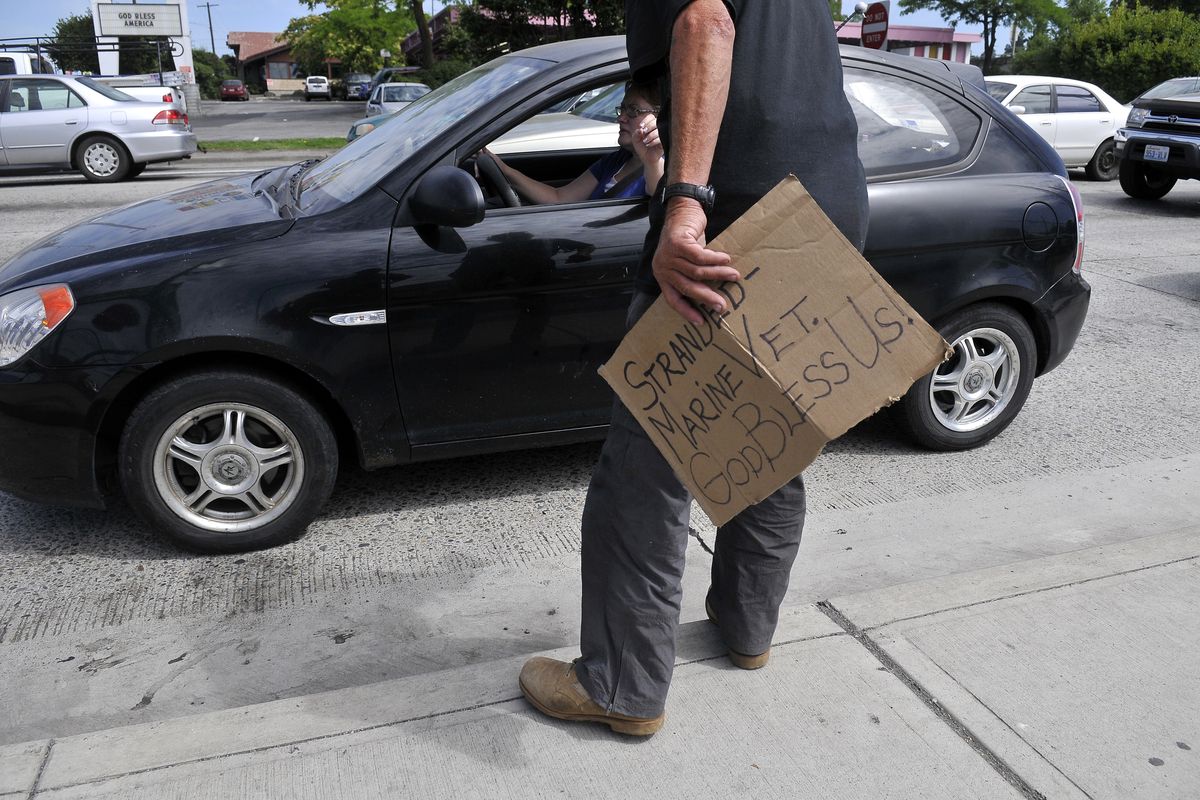 Richard Henderson accepts a few dollars from a motorist at the corner of Third and Division on Thursday. Henderson is a Vietnam veteran who says a panhandling ban would not stop him from seeking money from downtown drivers. (Jesse Tinsley)