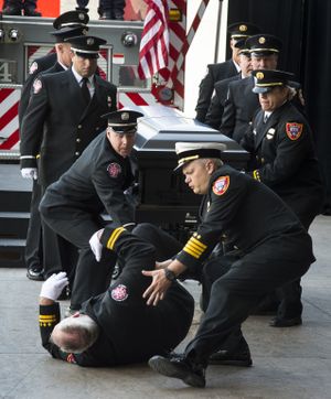 Serving as pallbearer for firefighter John Knighten last month, Capt. Mike Rose fainted during the public memorial service. Paramedics and emergency medical technicians who were attending the service quickly came to the aid of the veteran firefighter, including Brian Schaeffer, assistant fire chief, bending over Rose to the right. (Colin Mulvany)