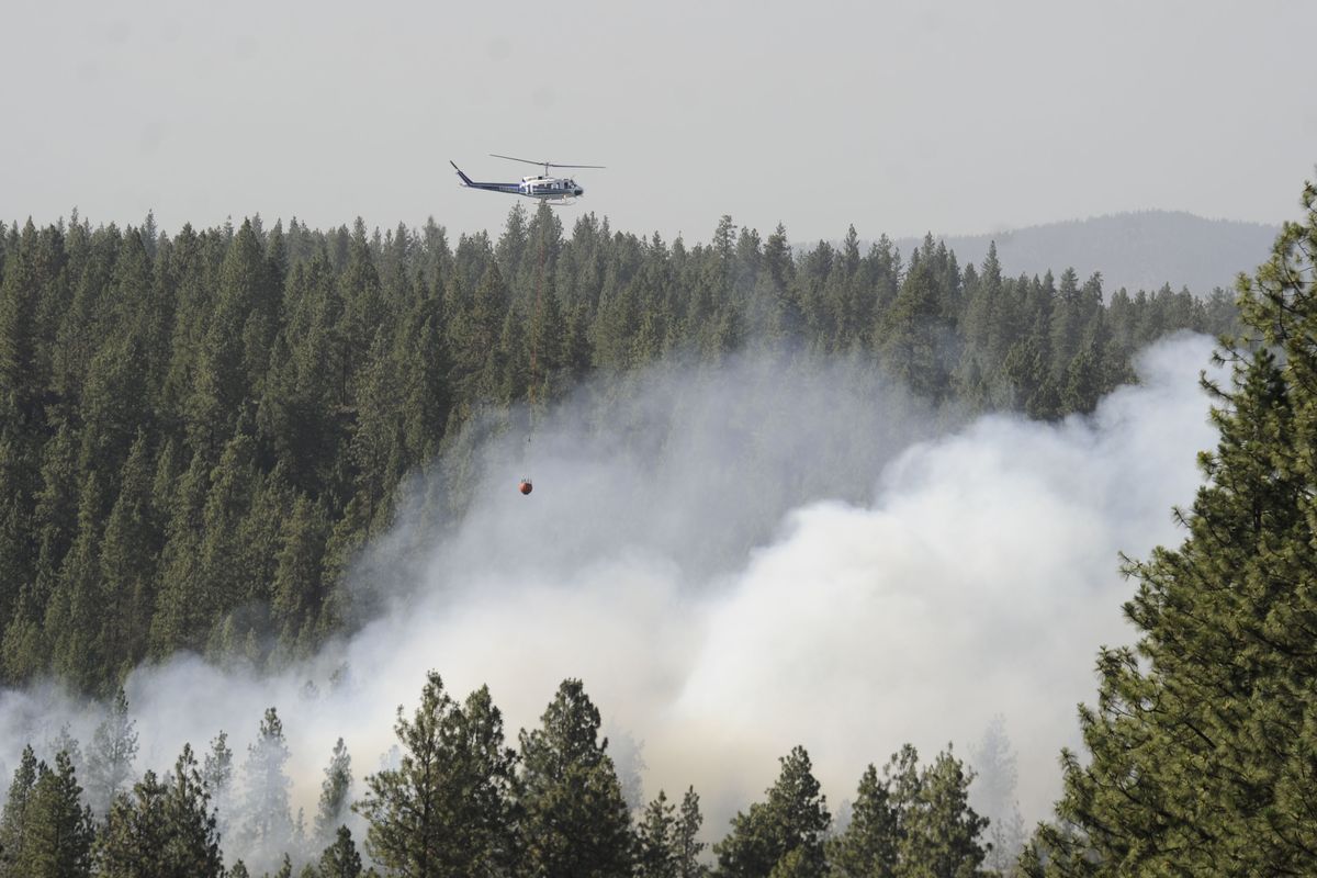 A helicopter fights a wildfire north of Indian Canyon golf course, Thursday, June 11, 2015 as a southwest wind pushes it northward. (Jesse Tinsley / The Spokesman-Review)