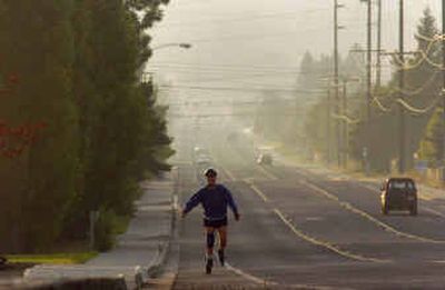 
A skater heads west on 57th Avenue early Tuesday morning as a smoky haze fills the sky at sunrise. The smoke is being blown into the region from wildfires in British Columbia. 
 (Christopher Anderson/ / The Spokesman-Review)