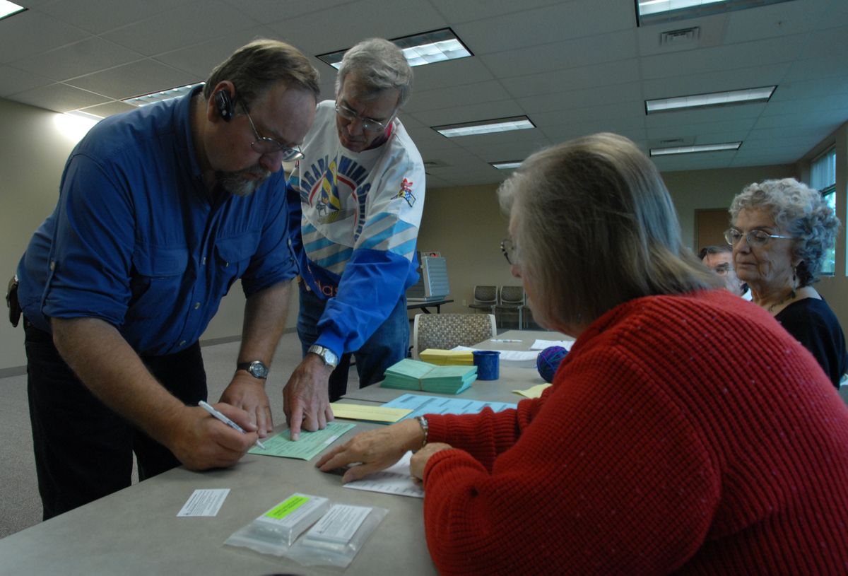 Dan Wilson, far left,  completes his ballot Tuesday with help from county elections office employees at CenterPlace in Spokane Valley. The Spokesman Review (Photos by KATE CLARK The Spokesman Review / The Spokesman-Review)