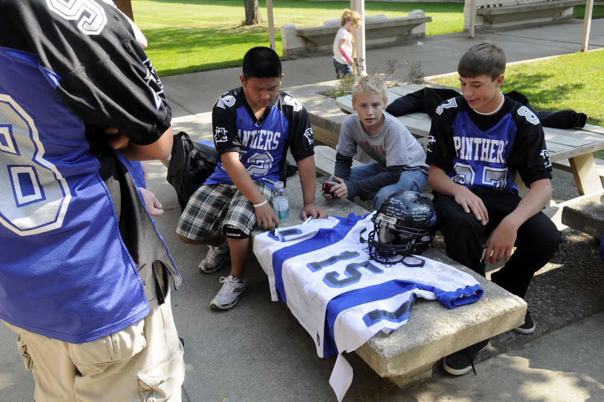 Valley Christian football players gather in the school’s courtyard Monday to remember their teammate Andrew “Drew” Swank, who  died Sunday of head injuries suffered in a game Friday. From left are sophomore Jun Ryn,  sixth-grader and the coach’s son Gabriel Puryear, and sophomore Ross Tabbert. (J. BART RAYNIAK / The Spokesman-Review)