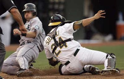 Seattle's  Willie Bloomquist is tagged out at home plate by Oakland catcher Kurt Suzuki. Associated Press
 (Associated Press / The Spokesman-Review)