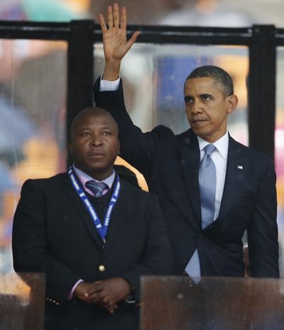 President Barack Obama waves standing next to the sign language interpreter after making his speech at the memorial service for former South African president Nelson Mandela at the FNB Stadium in Soweto near Johannesburg, Tuesday, Dec. 10, 2013.  South Africa's deaf federation said on Wednesday that the interpreter on stage for Mandela memorial was a 'fake', (Matt Dunham / Associated Press)