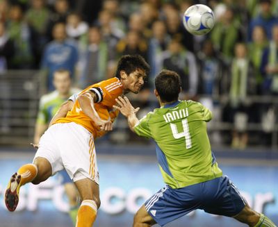 Former GU star Brian Ching of the Dynamo heads the ball in front of Sounders’ Patrick Ianni.  (Associated Press / The Spokesman-Review)