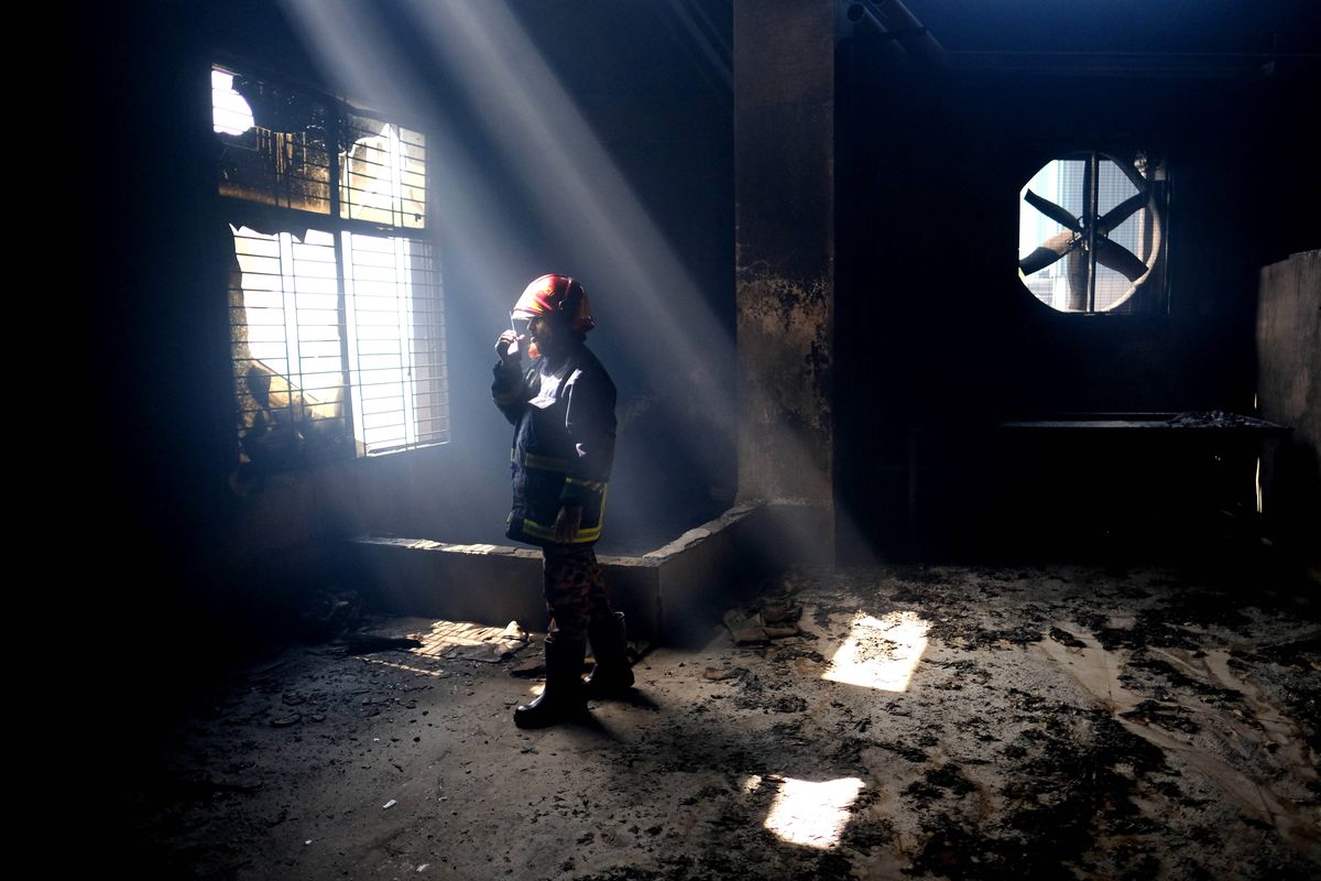 A firefighter communicates with his colleagues on a walkie talkie inside the burnt food and beverage factory in Rupganj, outside Dhaka, Bangladesh, Friday, July 9, 2021. At least 52 people died in a huge blaze that engulfed a food and beverage factory outside Bangladesh