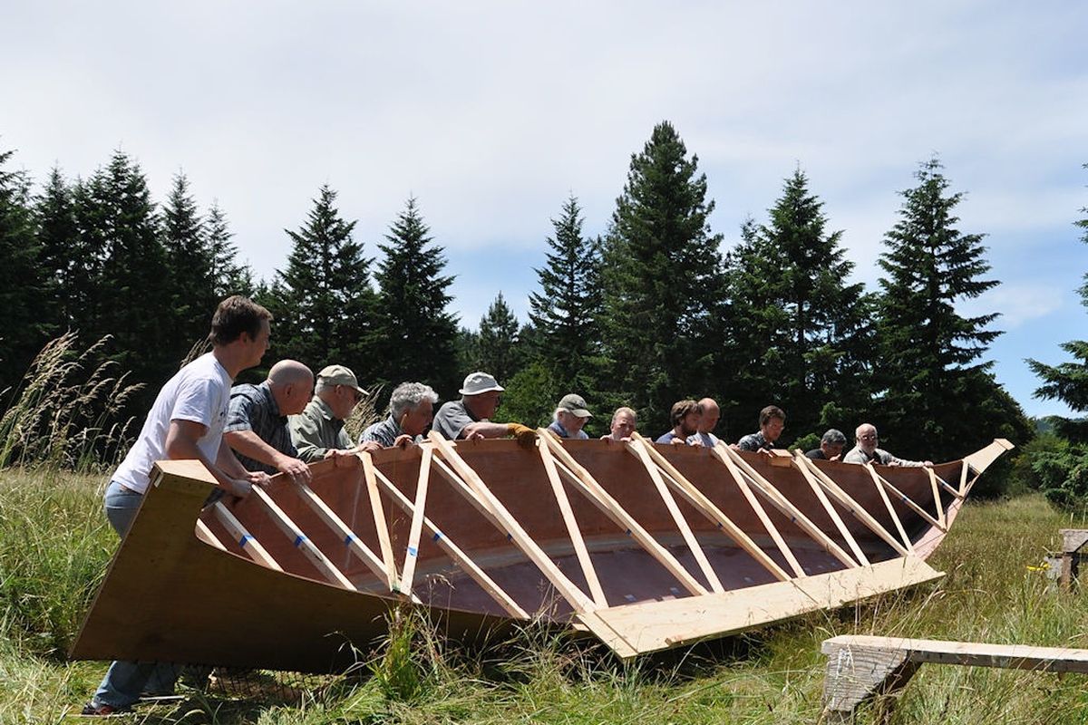 In this June 26, 2011, photo provided by Laura McCallum and taken in Veneta, Ore., a group of men help turn a canoe being built by John McCallum, owner and boatwright of Applegate Boatworks. Back in 1806, explorers Lewis and Clark stole a canoe from native Americans living on the Pacific Coast. More than 200 years later, William Clark