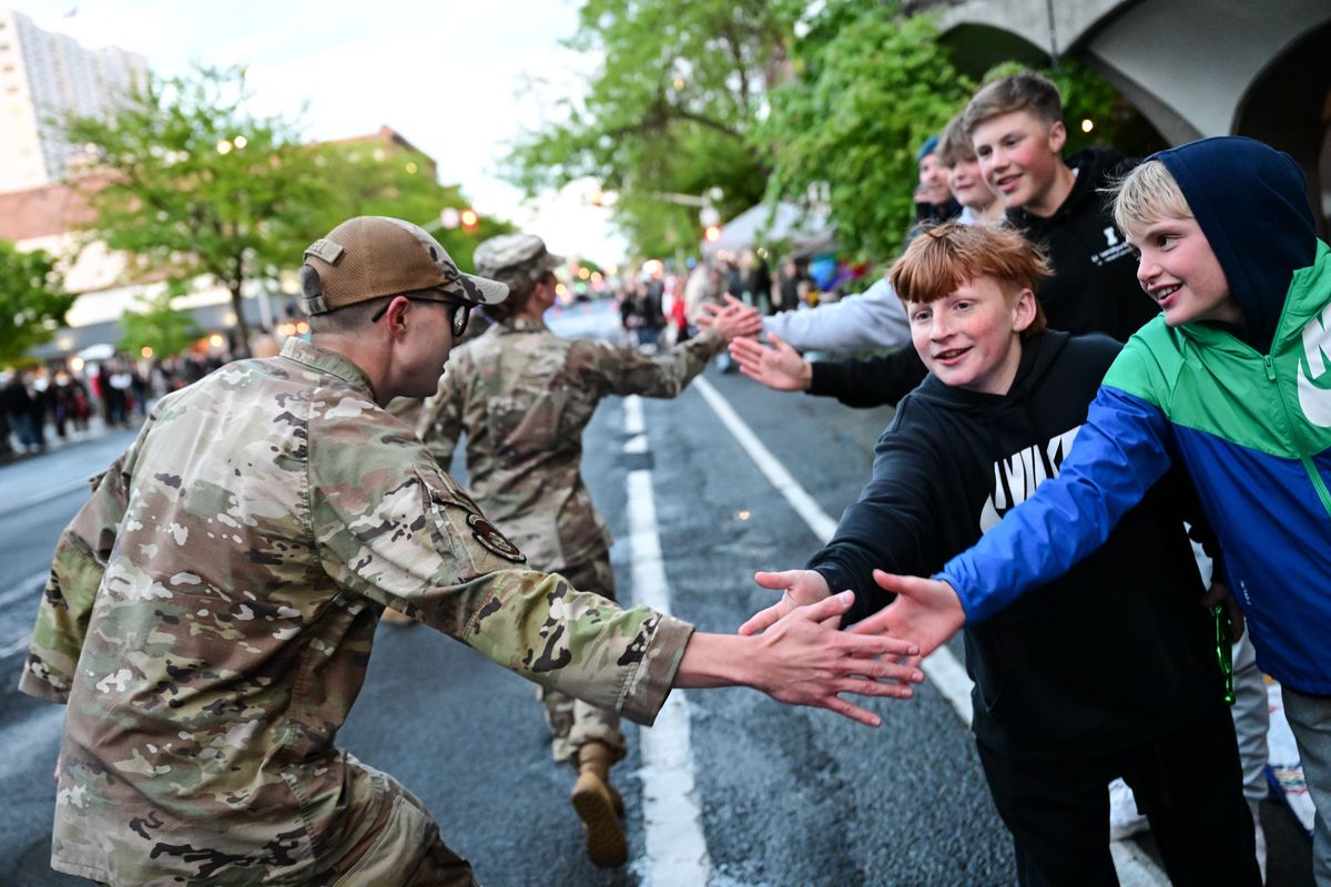 Carson Slick, right and Austin Spears, second right, grab high-fives from airmen during Saturday’s Lilac Festival Armed Forces Torchlight Parade.  (Tyler Tjomsland/The Spokesman-Review)