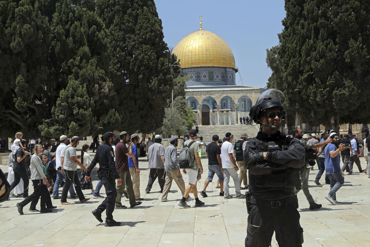 An Israeli police officer stands guard as Jewish men visit the Dome of the Rock Mosque in the Al Aqsa Mosque compound, during the annual mourning ritual of Tisha B