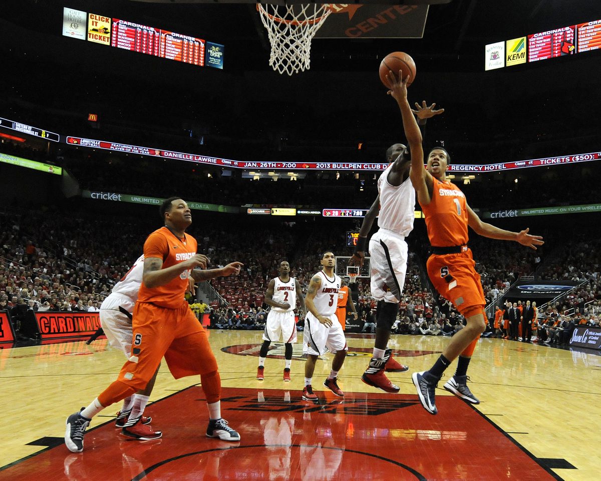 Syracuse guard Michael Carter-Williams, right, shoots a layup around the defense of Louisville
