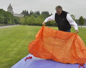 OLYMPIA -- Gov. Jay Inslee practices deploying a fire shelter during an annual exercise in the park below the Capitol at the start of fire season.  (Jim Camden)