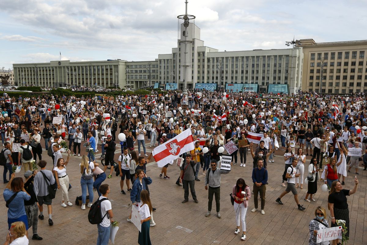 People, many holding old Belarusian national flags as they gather at Independent Square in the center of Minsk, Belarus, Friday, Aug. 14, 2020. Some thousands of people flooded the centre of the Belarus capital, Minsk, in a show of anger over a brutal police crackdown this week on peaceful protesters that followed a disputed election.  (Sergei Grits)