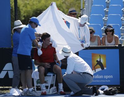Frank Dancevic of Canada receives assistance after collapsing in 108-degree heat at Australian Open. He finished, but lost his match. (Associated Press)