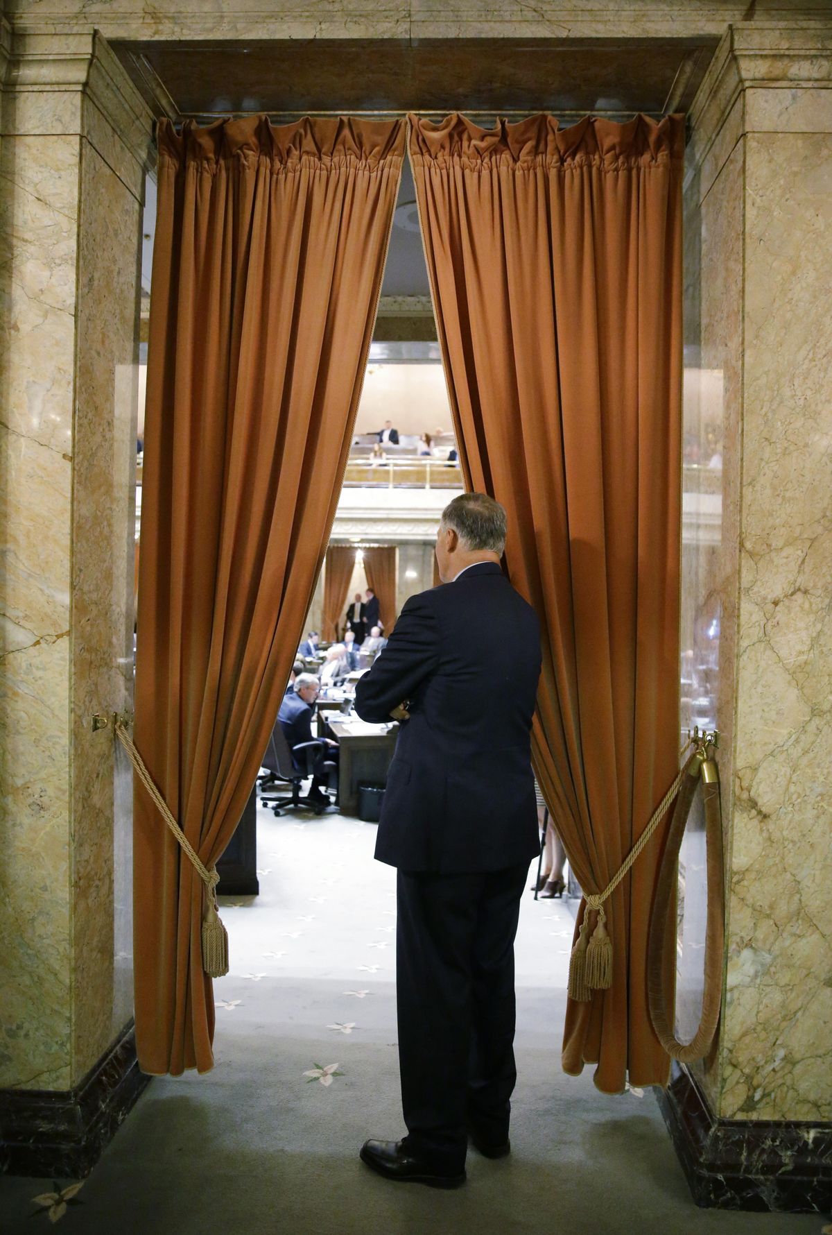 Washington Gov. Jay Inslee watches from the wings of the House chamber Friday during debate on the state operating budget at the Capitol in Olympia. (Ted S. Warren / Associated Press)