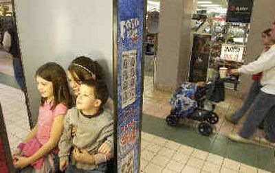 Nicole, 9, Angela, 13, and Jayson, 5, Barr of Post Falls sit in an automated photo kiosk at Silver Lake Mall on Christmas Eve, to make photos for their mother.
(Jesse Tinsley / The Spokesman-Review)