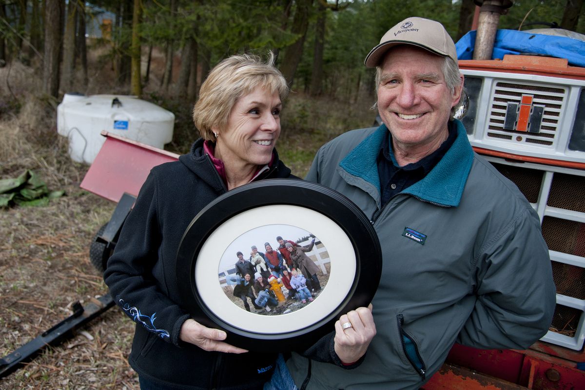 Susan and Val Taylor hold a Christmas picture of their family gathered around the new fire hydrant on their Colbert property in December 2011. The family had tried to dig wells and haul water for years before being hooked to Whitworth Water District lines. The water tank, at rear left, holds 350 gallons. Val said they made 67 trips to the Kellogg well in one summer. (Dan Pelle)