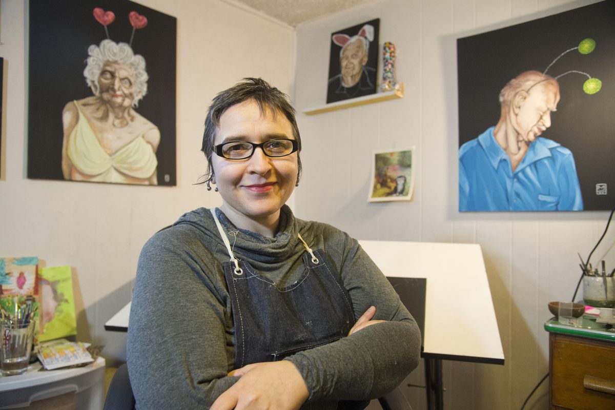 Melanie Lieb poses for a photo in her tiny basement studio at her north-side home, Saturday, Dec. 19, 2015. She is currently painting a series tentatively called “Young at Heart” of older people showing a silly side. She will hang these at the Liberty Building. Lieb also makes jewelry. (Jesse Tinsley / The Spokesman-Review)