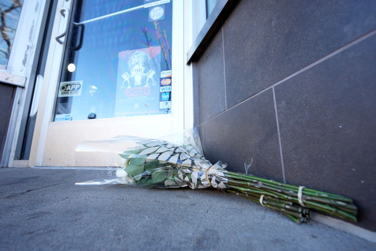 Bouquets of flowers are placed outside the door of a tattoo parlor in Denver, one of the scenes of a shooting spree that left five people dead Monday. (David Zalubowski)