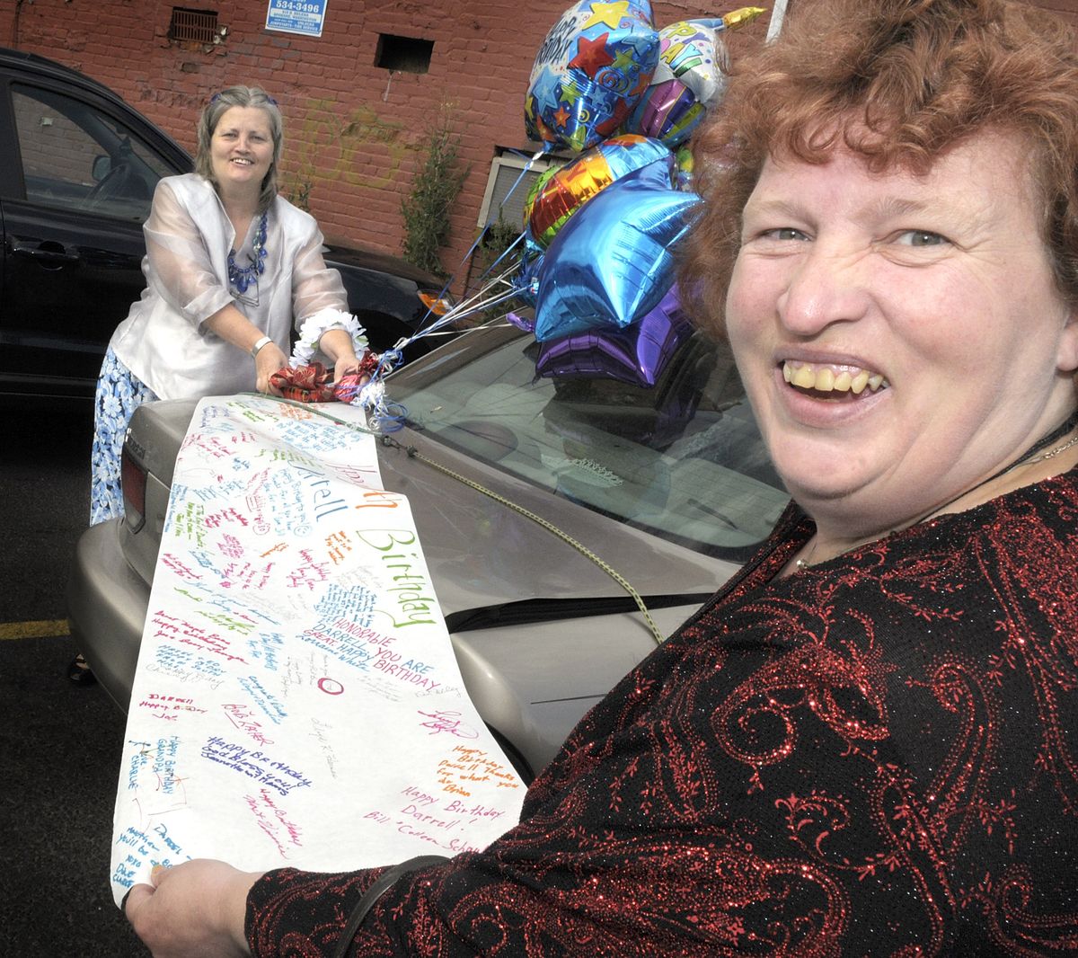 Lorraine White, left, and Linda Witty prepare a birthday surprise for Darrell Jones at The Donut Parade in Spokane. (Christopher Anderson / The Spokesman-Review)