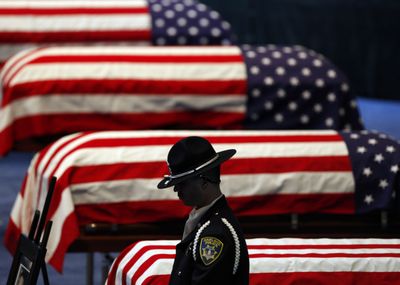 An Oakland police honor guard stands his post next to the flag-draped caskets of four Oakland police officers in Oracle Arena on Friday in Oakland, Calif.  (Associated Press / The Spokesman-Review)